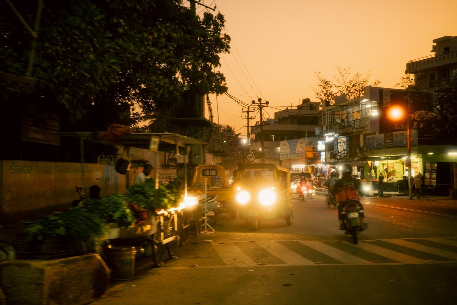 Bengaluru street at dusk with an auto and bikes